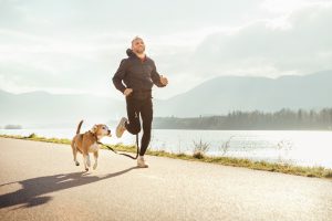 Man running with dog next to lake
